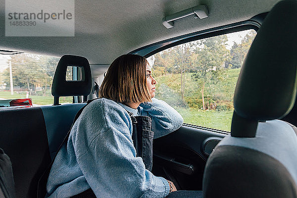 Frau  die auf dem Rücksitz eines Autos aus dem Fenster schaut