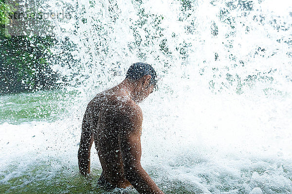 Mann unter erfrischendem Wasserfall