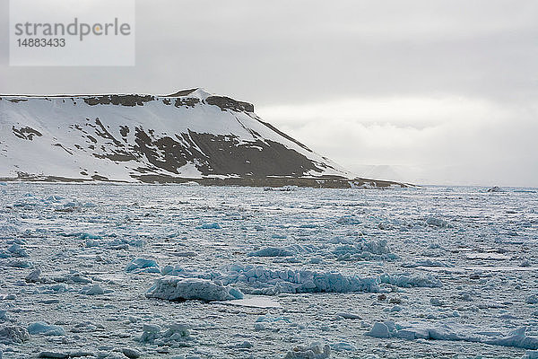 Gefrorene Landschaft und entfernter schneebedeckter Berg  Wahlenberg Fjord  Nordaustlandet  Svalbard  Norwegen