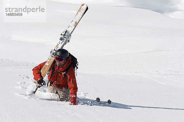 Männlicher Skifahrer stapft durch Tiefschnee den Berg hinauf  Alpe-d'Huez  Rhône-Alpes  Frankreich