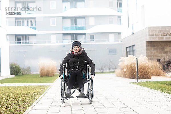 Frau im Rollstuhl in einem Wohngebiet