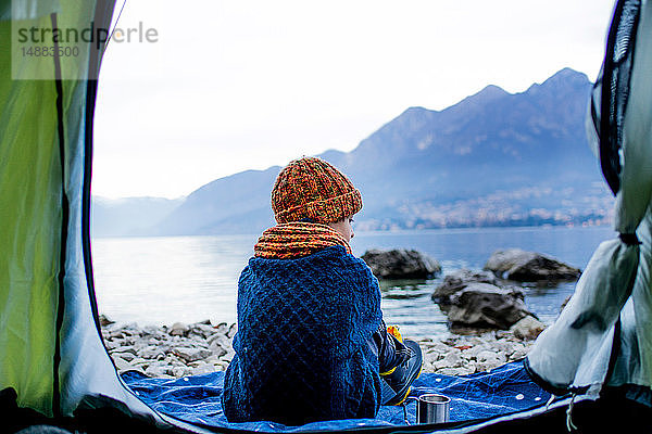 Junge sitzt auf einer Decke am Zelt  Rückansicht  Comer See  Onno  Lombardei  Italien