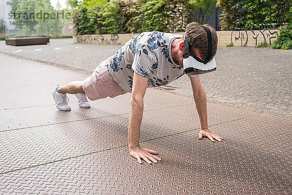 Mann in Push-up-Position mit Virtual-Reality-Brille  Berlin  Deutschland