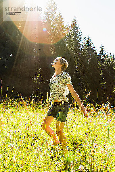 Frau tanzt zwischen wilden Blumen im Wald  Sonthofen  Bayern  Deutschland