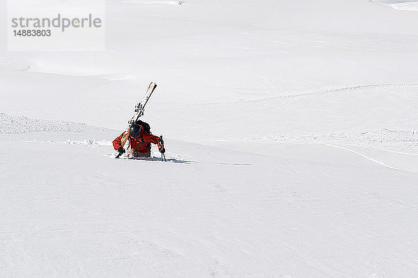 Männlicher Skifahrer stapft durch Tiefschnee den Berg hinauf  Alpe-d'Huez  Rhône-Alpes  Frankreich