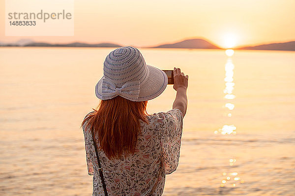 Tourist fotografiert Sonnenuntergang am Strand