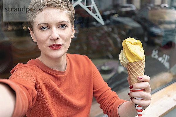 Frau  die sich mit Eiscreme vor dem Laden selbstständig macht