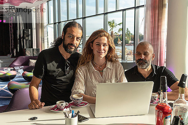 Gruppe von drei Unternehmern  die einen Laptop benutzen und Kaffee im Büro trinken