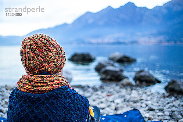 Junge sitzt auf einer Decke am Seeufer  Rückansicht  Comer See  Onno  Lombardei  Italien