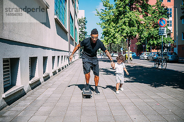 Vater lehrt Sohn Skateboardfahren auf dem Bürgersteig