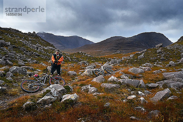 Männlicher Mountainbiker bei einer Pause in einer Bergtal-Landschaft  Achnasheen  Schottische Highlands  Schottland