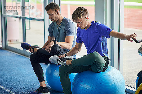 Läufer strecken sich auf Übungsbällen in der Indoor-Laufbahn