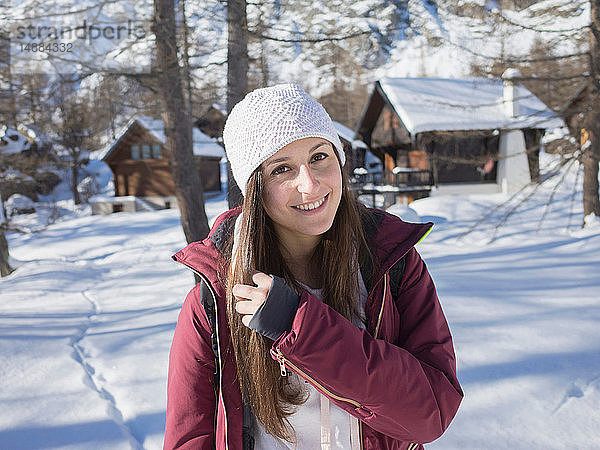 Junge Frau mit Strickmütze im verschneiten Wald  Porträt  Alpe Ciamporino  Piemont  Italien