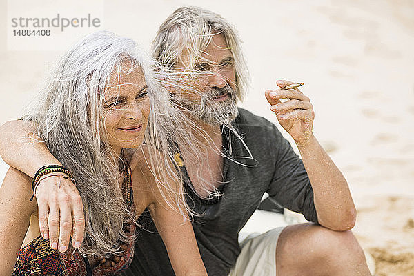 Porträt eines älteren Hippie-Paares beim Rauchen am Strand