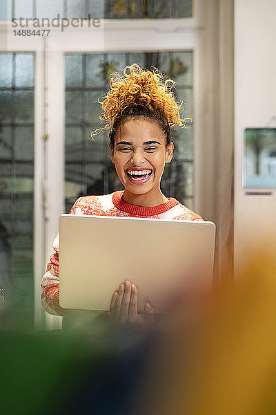 Junge Frau arbeitet in einem Modegeschäft und benutzt einen Laptop