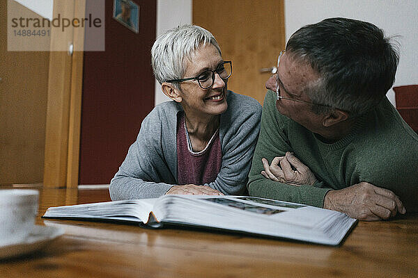 Glückliches älteres Ehepaar zu Hause auf dem Boden liegend mit Fotoalbum