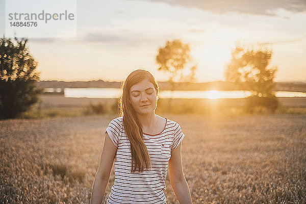 Porträt einer jungen Frau  die sich bei Sonnenuntergang in der Natur entspannt