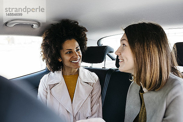 Zwei glückliche Frauen sitzen auf dem Rücksitz eines Autos