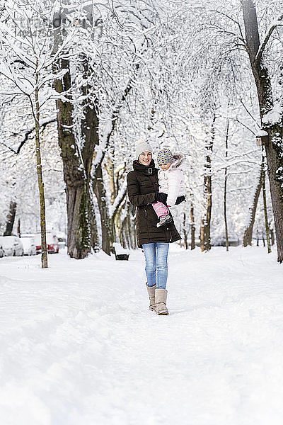 Glückliche Mutter geht mit Tochter in Winterlandschaft spazieren