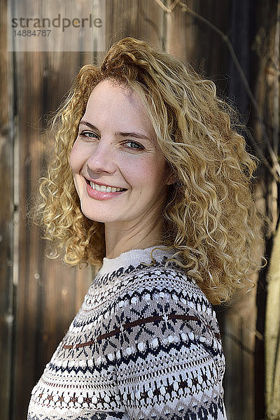 Blonde Frau mit lockigem Haar lächelt  norwegischer Pullover