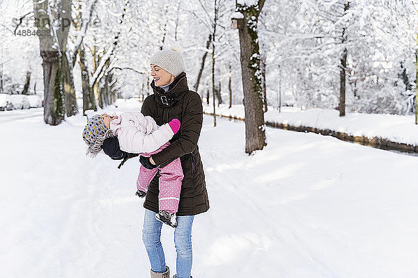 Glückliche Mutter spielt mit Tochter in Winterlandschaft