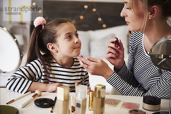 Mutter und Tochter schminken sich gemeinsam mit Lippenstift