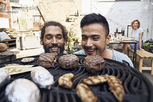 Freunde bereiten Fleisch für ein Barbecue im Hinterhof