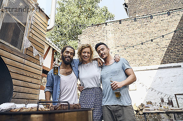 Freunde beim Grillen im Hinterhof  bei der Zubereitung von Fleisch auf dem Grill