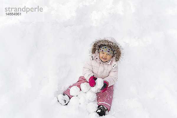 Süßes kleines Mädchen spielt im Winter mit Schnee