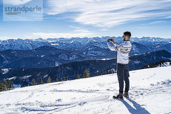 Deutschland  Bayern  Brauneck  Mann im Winter in den Bergen beim Fotografieren