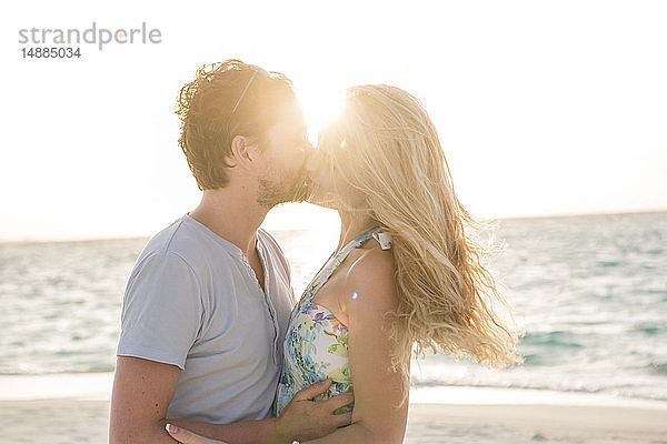 Glückliches Paar küsst sich am Strand