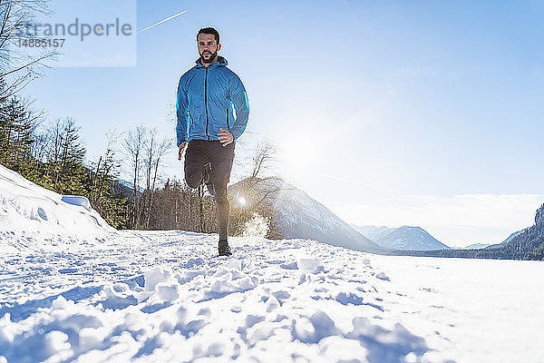 Deutschland  Bayern  sportlicher Mann rennt im Winter durch Schnee