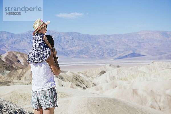 USA  Kalifornien  Death Valley National Park  Twenty Mule Team Canyon  Rückenansicht einer Mutter  die ein Mädchen trägt