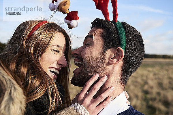 Glückliches  sorgenfreies Paar mit weihnachtlichem Kopfschmuck auf dem Land