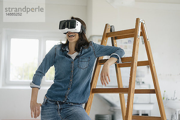 Frau mit VR-Brille  auf Leiter lehnend