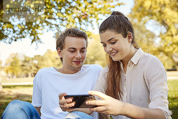 Junges Paar betrachtet Smartphone in einem Park