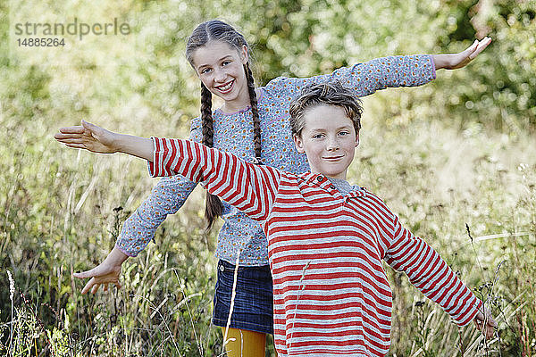 Porträt eines Jungen und seiner älteren Schwester beim Spielen in der Natur