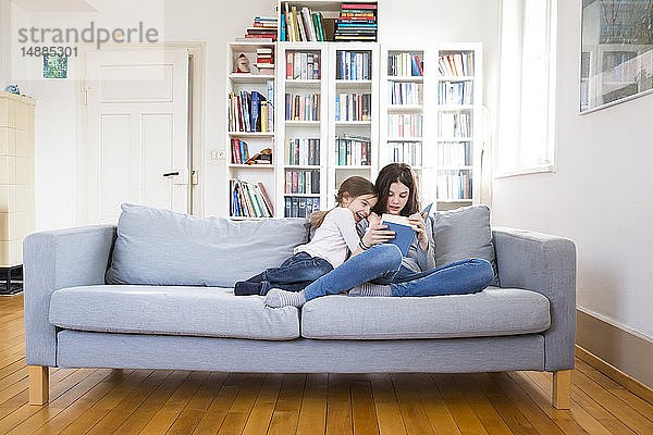 Schwestern sitzen auf der Couch  lesen Buch