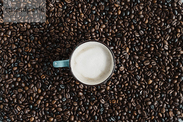 Tasse Weißkaffee zwischen Kaffeebohnen