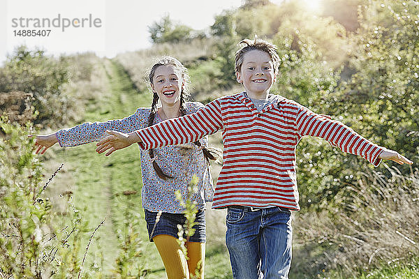 Porträt eines Jungen und seiner älteren Schwester beim Spielen in der Natur