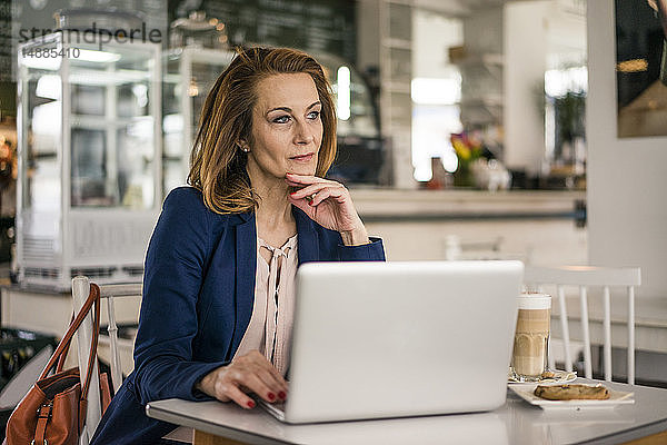 Geschäftsfrau sitzt im Café  isst zu Mittag  arbeitet am Laptop