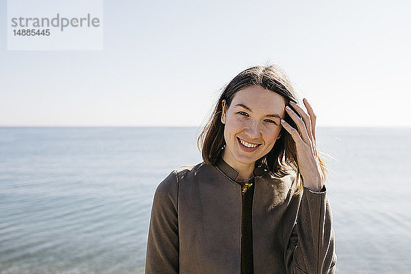 Porträt einer lächelnden Frau mit dem Meer im Hintergrund