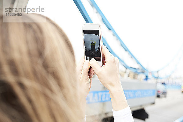 UK  London  Frau  die mit ihrem Smartphone Fotos von der Tower Bridge macht