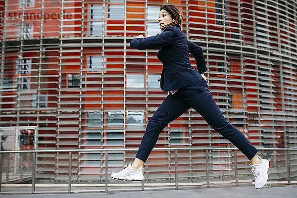 Geschäftsfrau springt in der Luft vor einem Bürogebäude in der Stadt