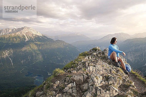 Österreich  Tirol  Frau auf Wanderung in den Bergen auf dem Gipfel sitzend