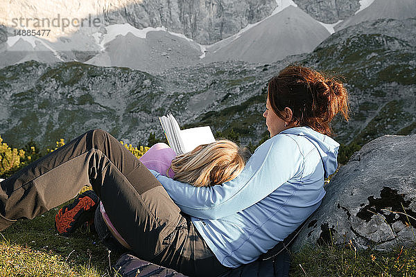 Österreich  Tirol  Mutter und Tochter lesen Buch in Berglandschaft
