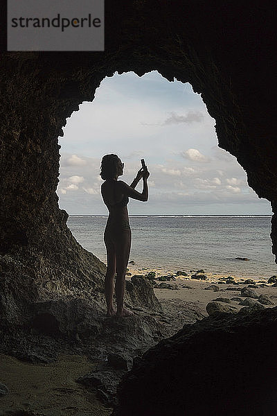 Junge Frau in Höhle  die ein Foto macht