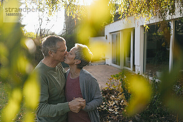 Zärtliches Seniorenpaar küsst sich im Garten