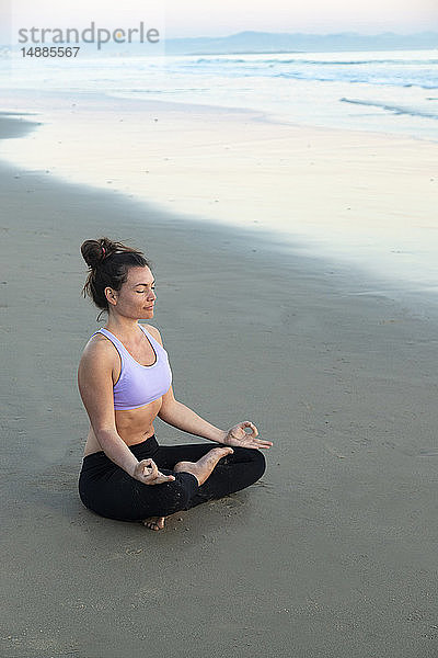 Frau  die abends am Strand meditiert