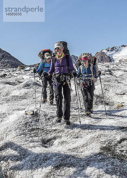 Grönland  Sermersooq  Kulusuk  Schweizer Alpen  drei lächelnde Menschen beim Wandern in verschneiter Berglandschaft